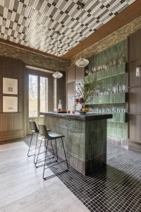 Barra en tonos negros y verdes en el Espacio Impar Capital, diseño de Impar Design con azulejos Imagine Concept, ejemplo de barras y mostradores protagonistas en el diseño de interiores.