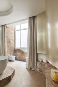 Cuarto de baño Origehm diseñado por Pilsferrer para Strohm Teka con revestimientos metálicos Homapal, tonos neutros, piedra natural y diseño contemporáneo.