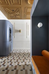 Zona de estar de “La Unidad” diseñada por Lemon Studio para Schmidt, con mobiliario modular azul, chimenea Dekton Somnia, mosaico Hisbalit y paleta cálida de tonos tierra.